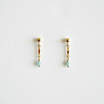 Pair of gold earrings with small beads on a light gray background