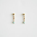Pair of gold earrings with small beads on a light gray background