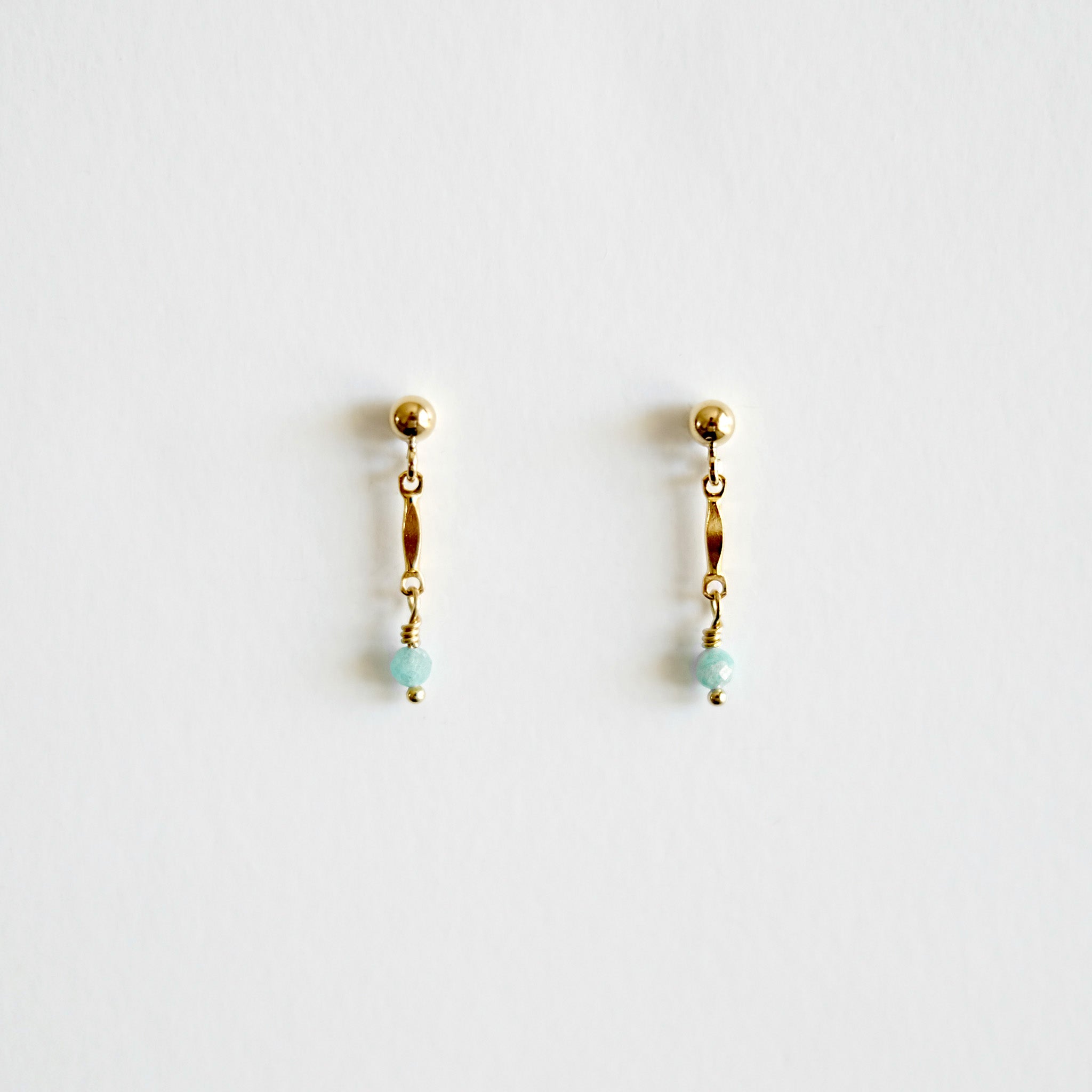 Pair of gold earrings with small beads on a light gray background