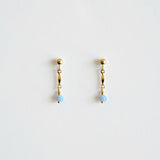 Pair of gold earrings with blue beads on a light gray background