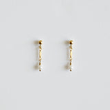 Pair of gold earrings with pearl drops on a light gray background
