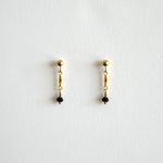 Pair of gold earrings with black beads on a white background