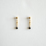 Pair of gold earrings with black beads on a white background