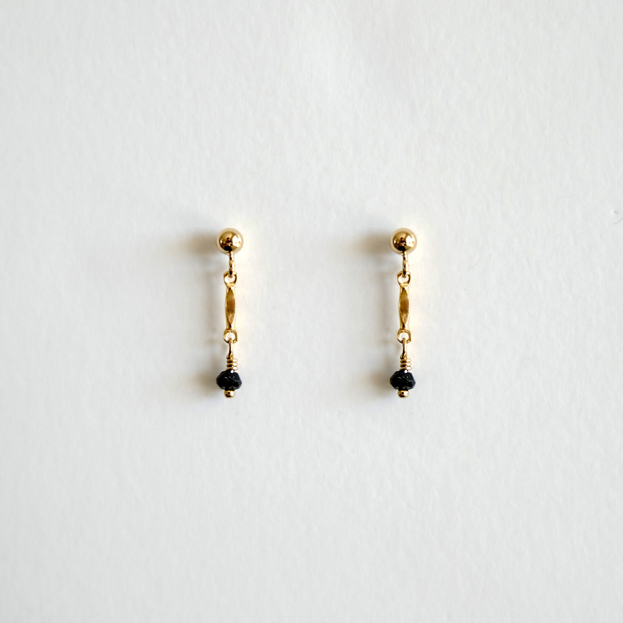 Pair of gold earrings with black beads on a white background