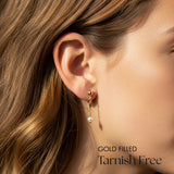 Gold filled earring worn by a person with text 'Gold Filled Tarnish Free' on a blurred background