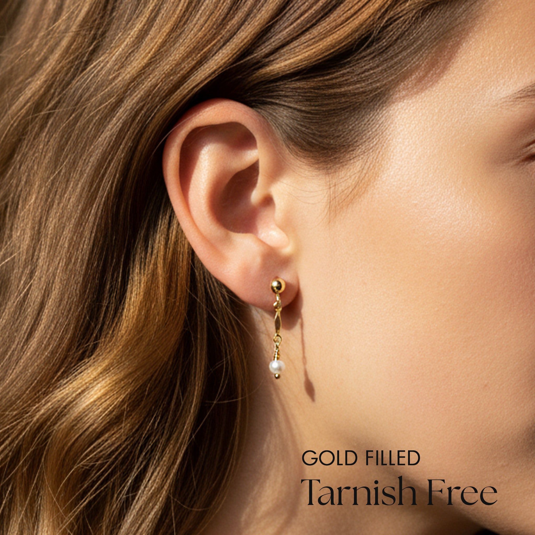 Gold filled earring worn by a person with text 'Gold Filled Tarnish Free' on a blurred background
