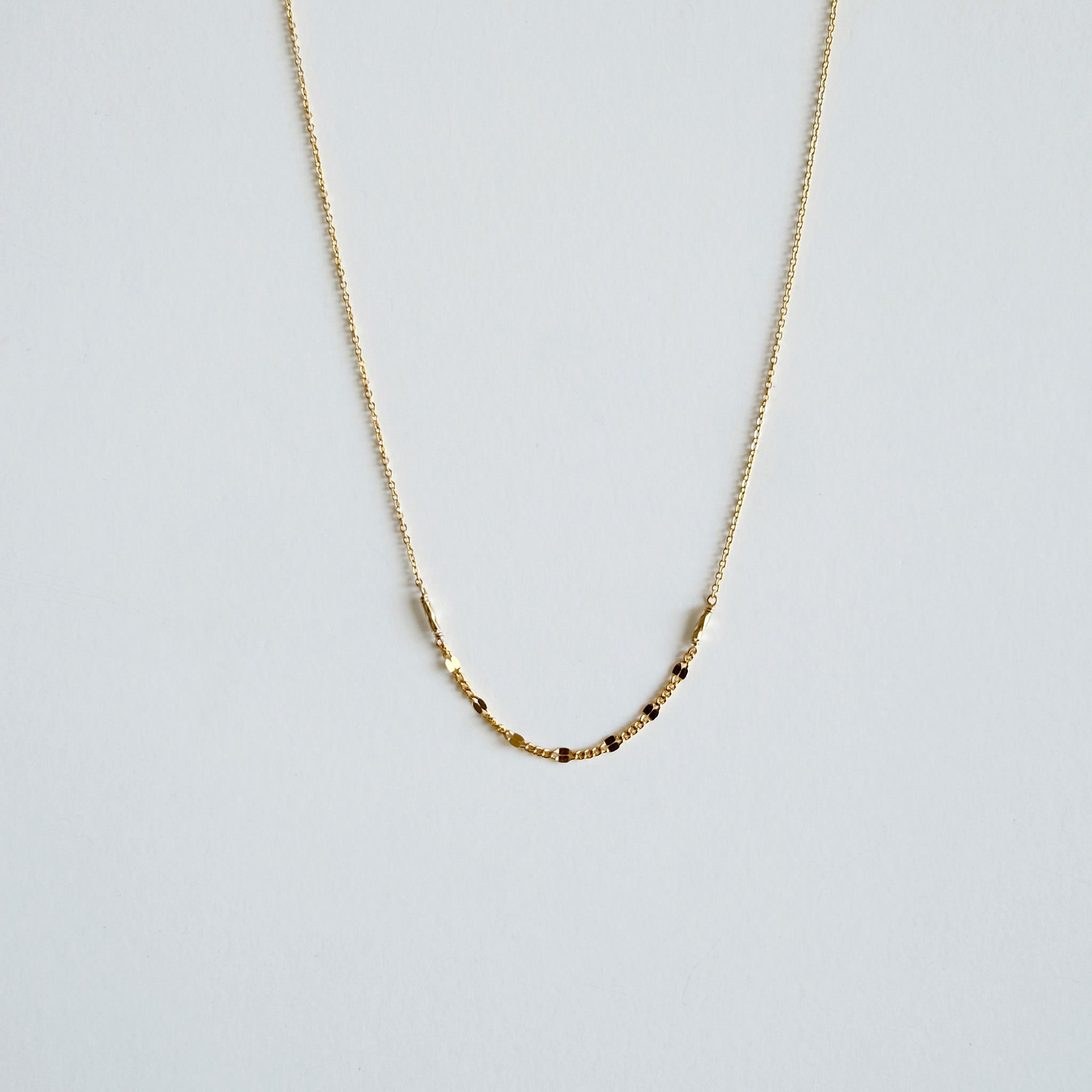 Gold necklace on a light gray background