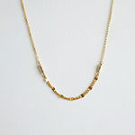 Gold necklace on a light gray background