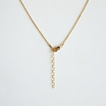 Gold necklace with clasp with extention chain on a light gray background