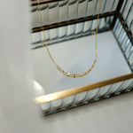 Gold necklace on a white surface with a blurred background