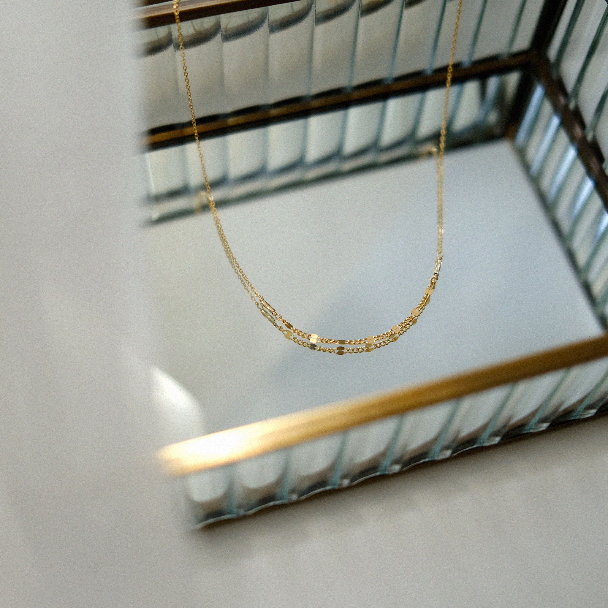 Gold necklace on a white surface with a blurred background