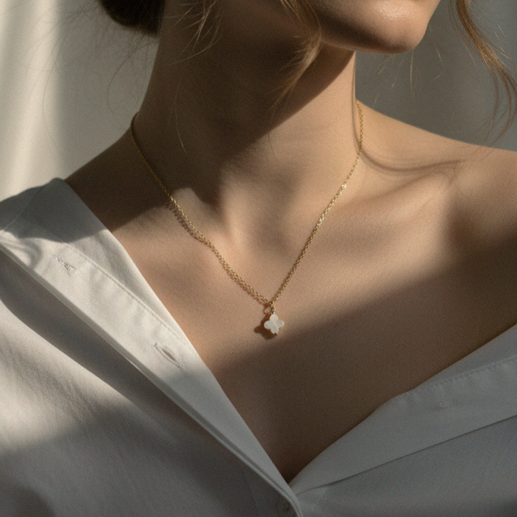 Close-up of a person wearing a delicate gold necklace with a small pendant.