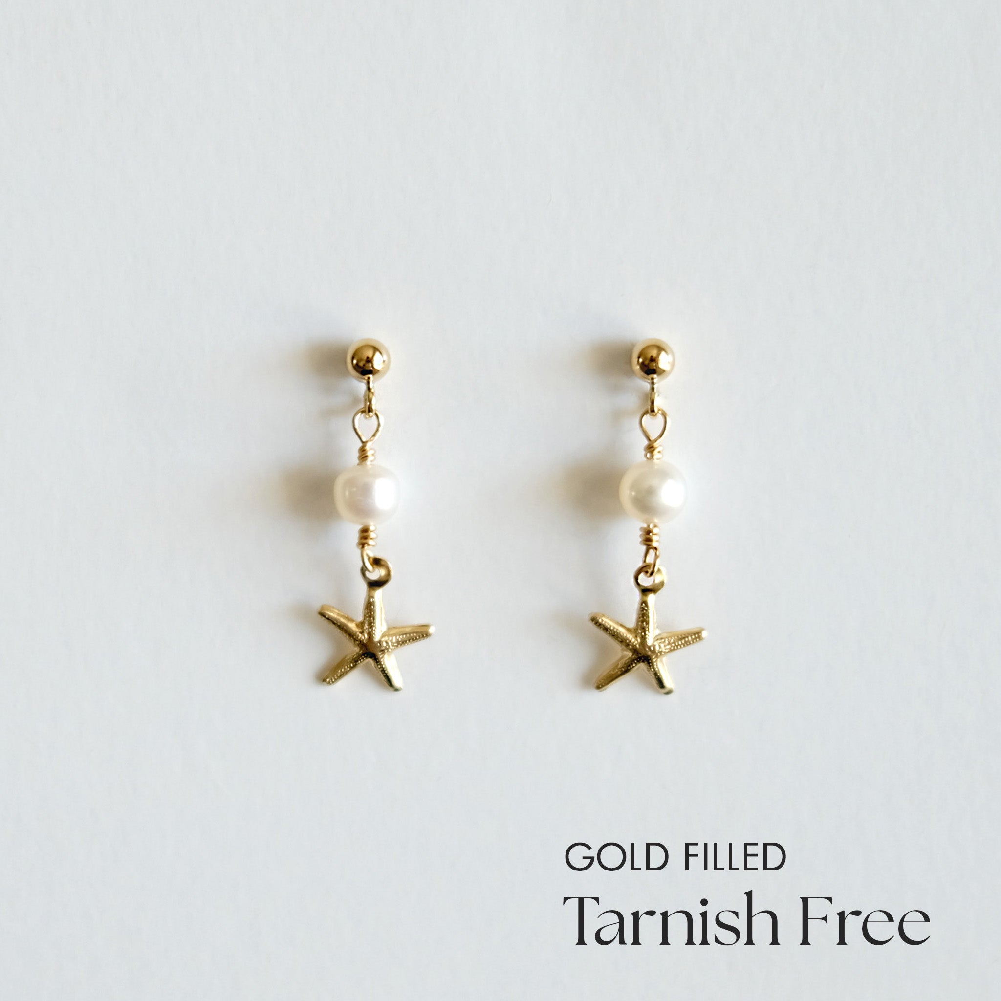 Gold-filled starfish earrings with pearls on a light gray background
