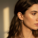 Close-up of a woman wearing earrings with a warm light background