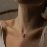 Close-up of a person wearing a gold necklace with a blue pendant.