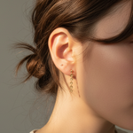 Close-up of a person wearing gold earrings with a neutral background