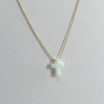 Gold necklace with a small cross pendant on a light gray background