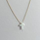 Gold necklace with a small cross pendant on a light gray background