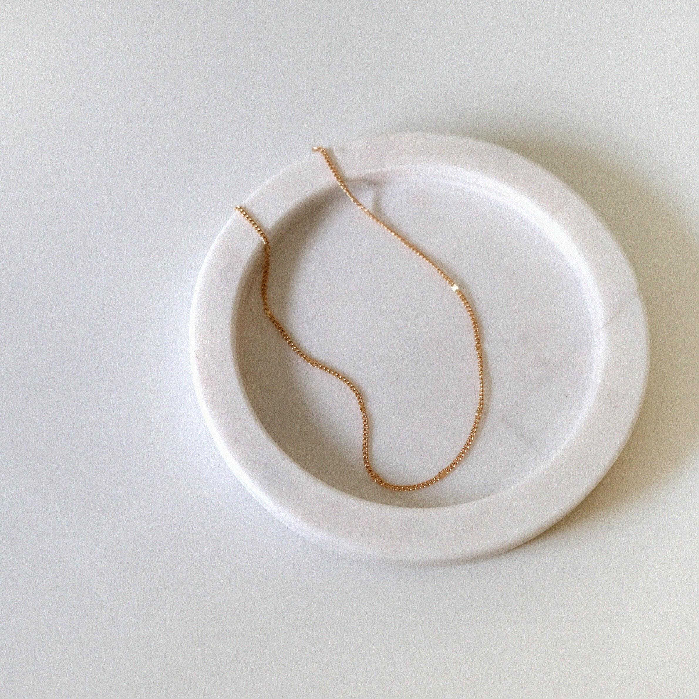 Ally Chain Anklet displayed on a soft light pink tray, highlighting its subtle shimmer and delicate chain