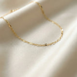 Gold chain necklace on a soft beige fabric background