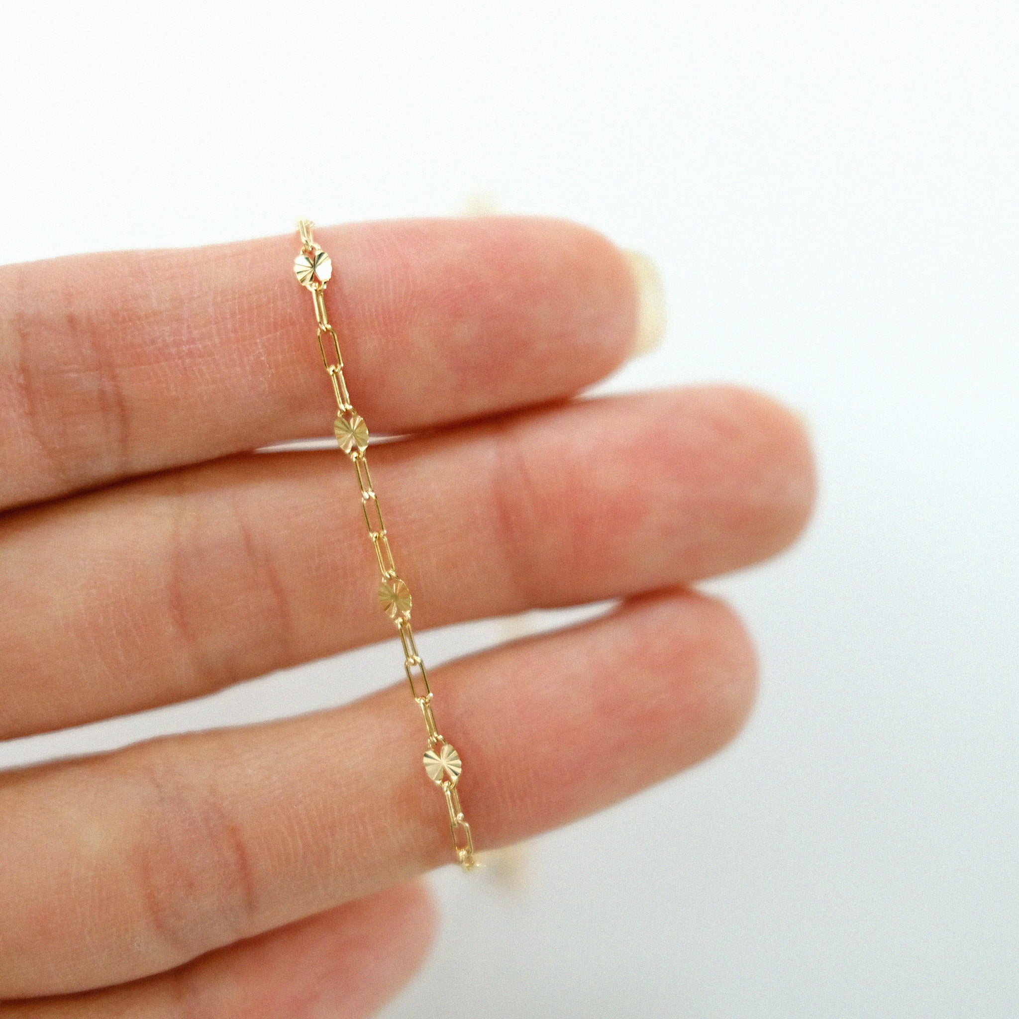 Gold chain bracelet on a person's wrist against a white background