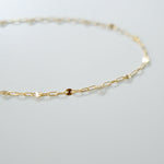 Gold chain necklace on a light gray background