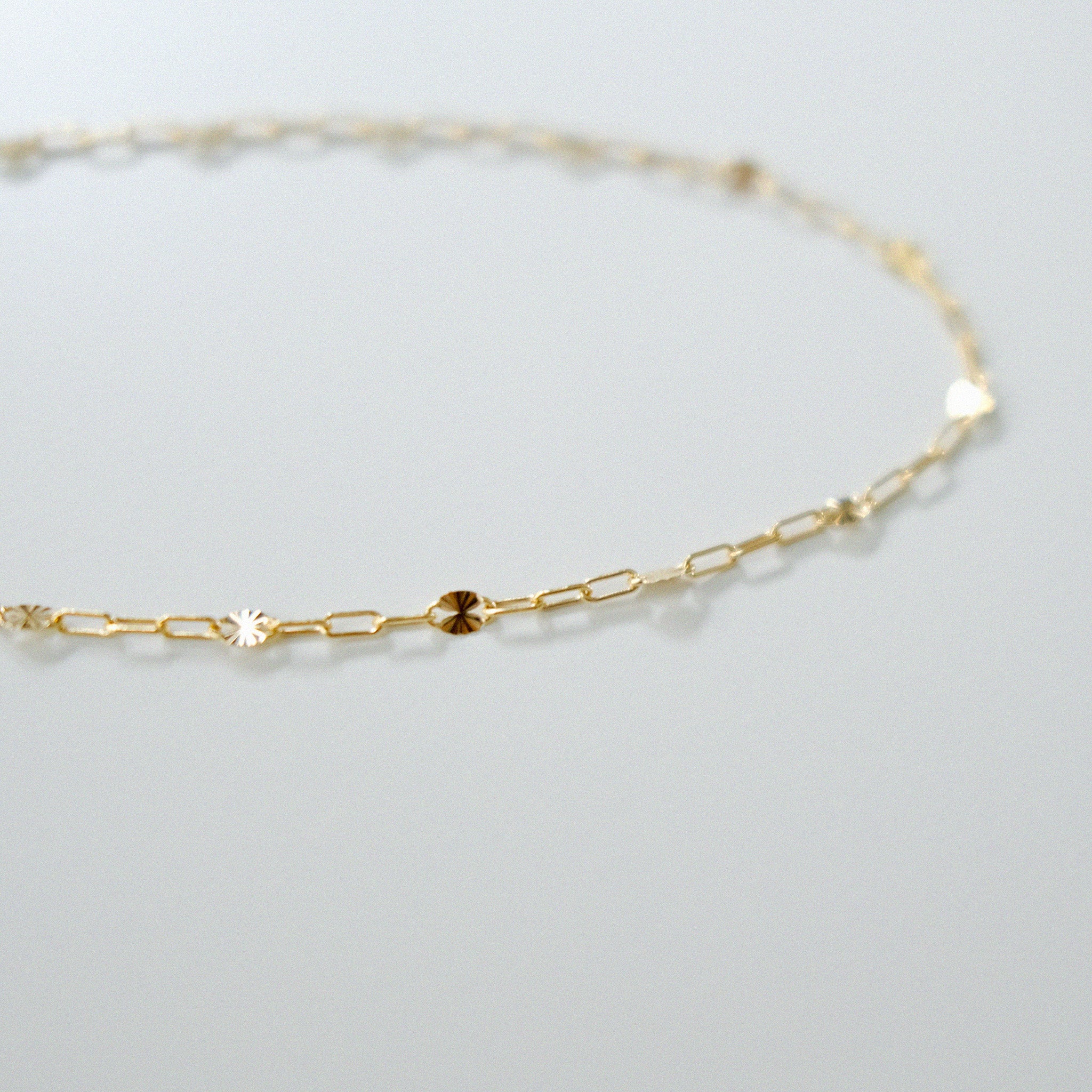 Gold chain necklace on a light gray background
