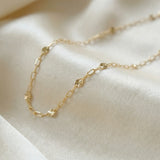 Gold chain necklace on a soft beige fabric background