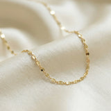 Gold chain necklace on a soft beige fabric background