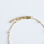 Gold chain bracelet on a light gray background