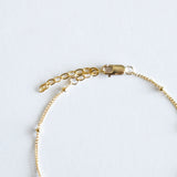 Gold chain bracelet on a light gray background