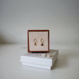 Product presentation of Celina disc Earrings in branded box, styled on white surface with clean background