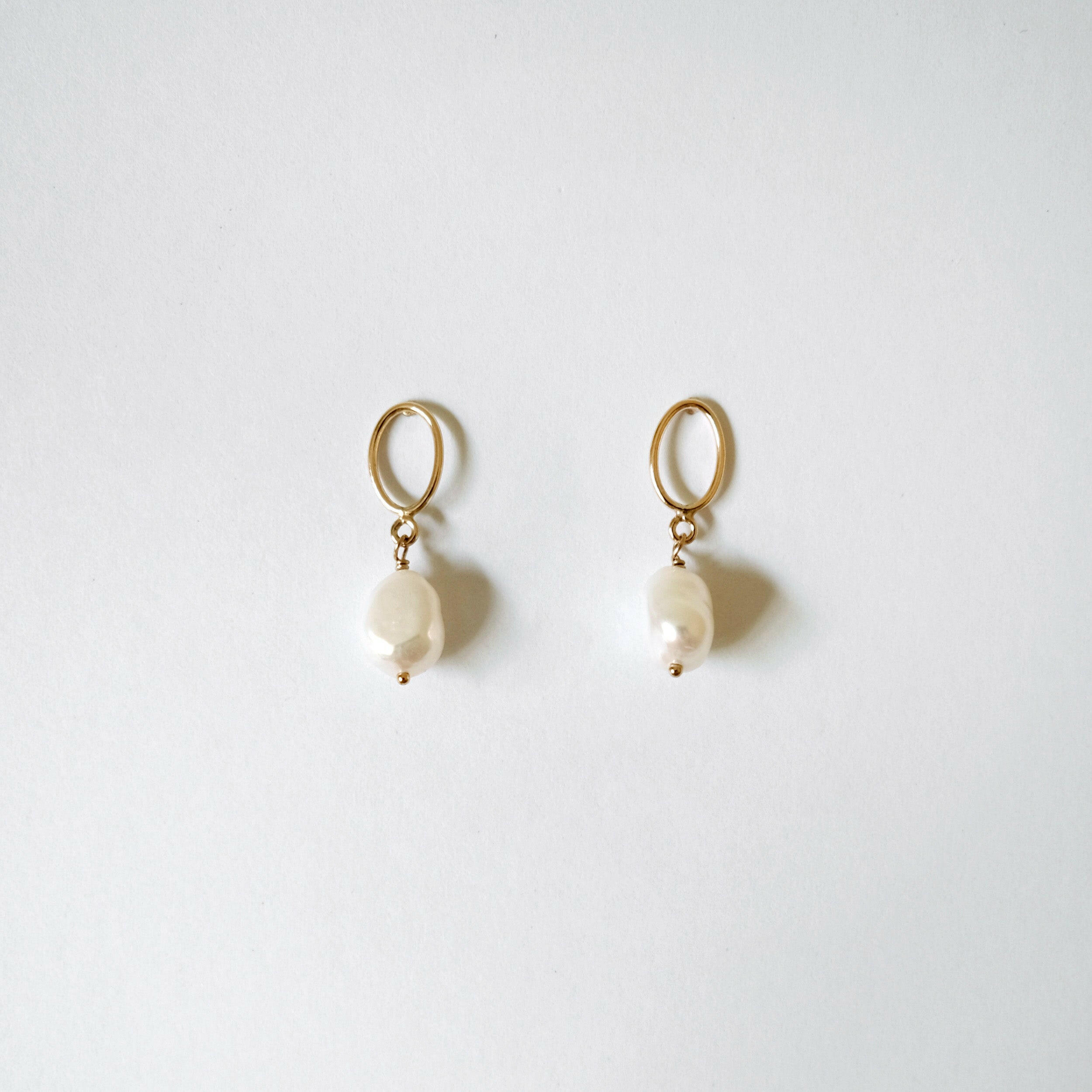 Gold-filled stud earrings with suspended freshwater pearls in organic form"

