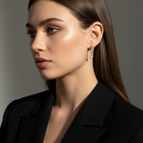 Close-up of a woman wearing gold earrings with a gray background