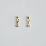 Gold earrings with small round stones on a light gray background