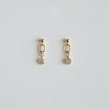 Gold earrings with small round stones on a light gray background