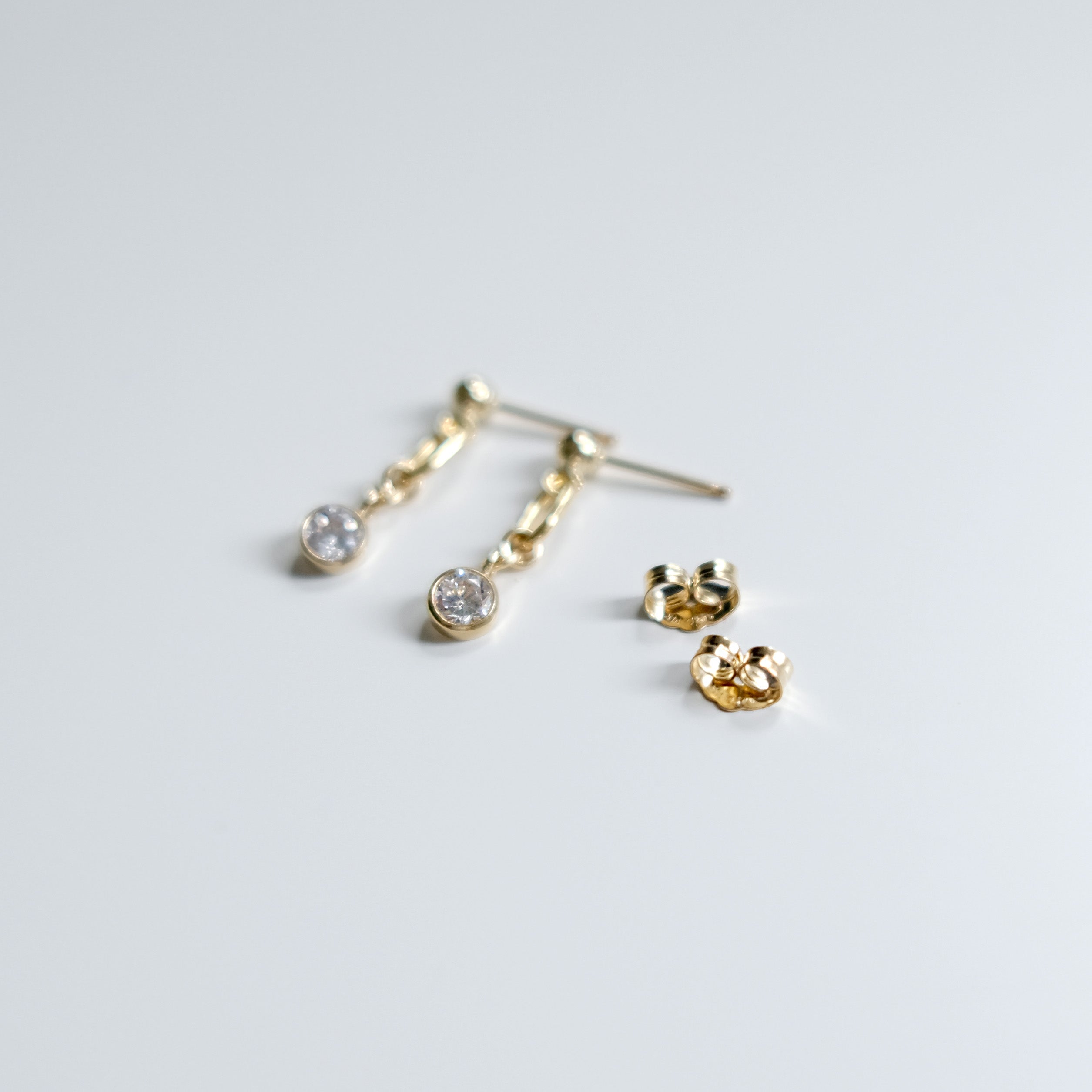 Gold earrings on a light gray background