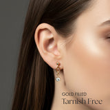 Close-up of a woman wearing gold earrings with a gray background