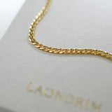 Gold chain on a light gray surface with 'LAONDRIM' branding.