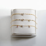 Set of gold filled custom bracelets with small charms on a white bracelet holder