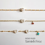 Three gold filled bracelets with letter beads on a light gray background
