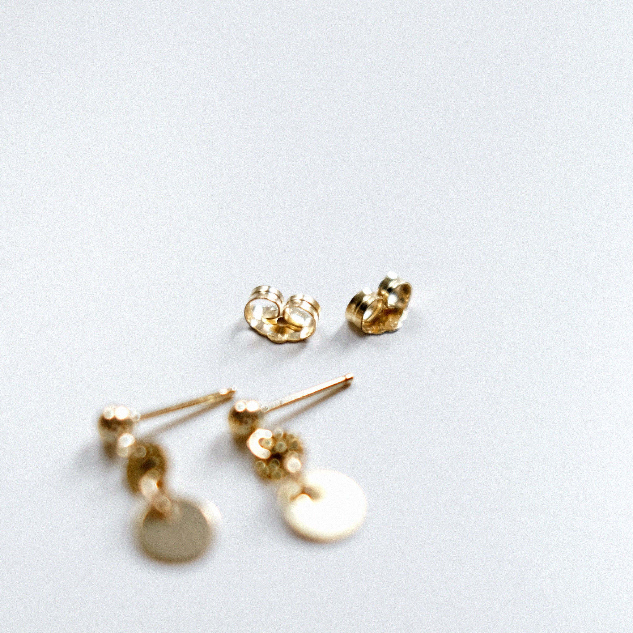 Gold earrings on a light gray background