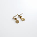 Gold earrings with round pendants on a white background