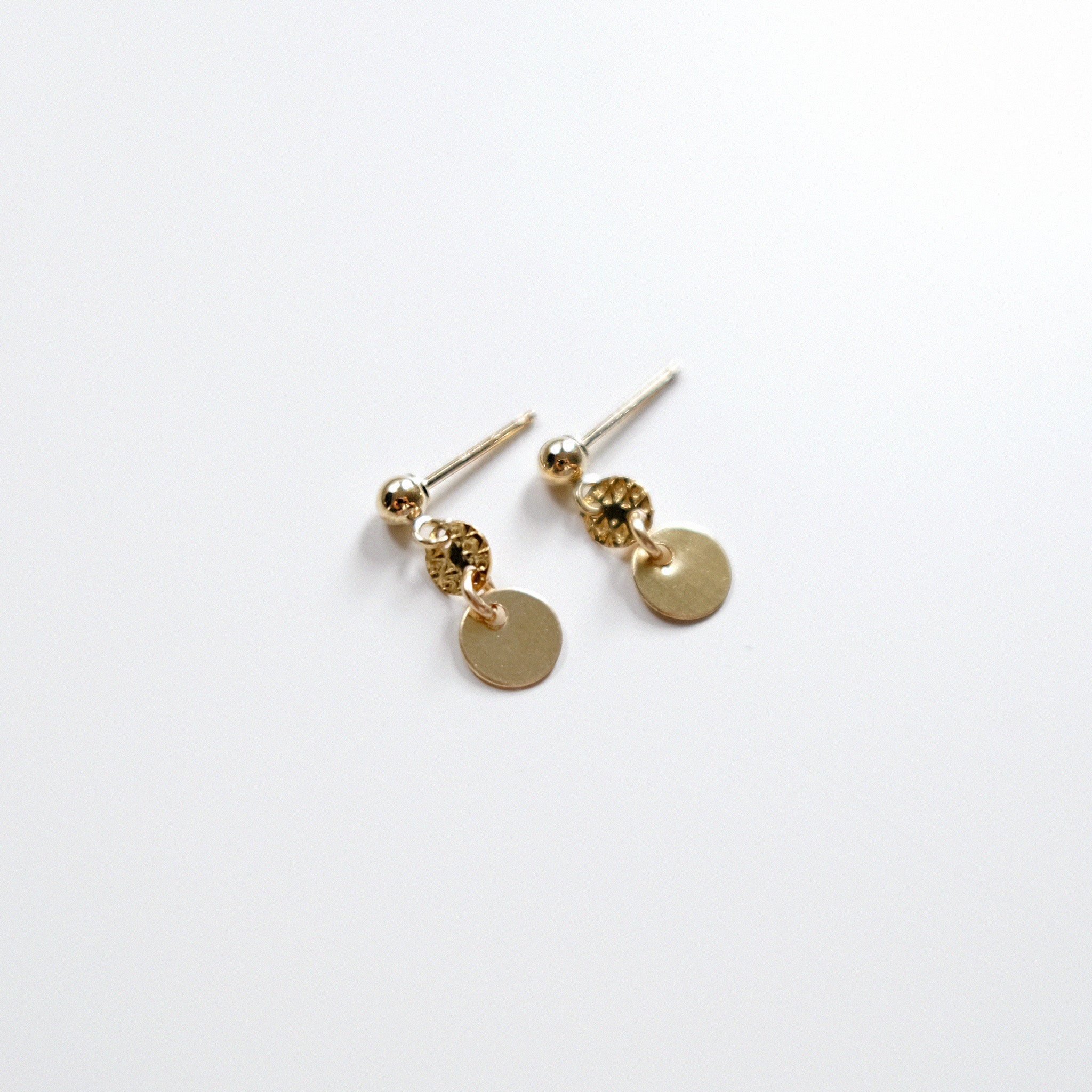 Gold earrings with round pendants on a white background