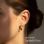 Gold filled earrings worn by a person with a neutral background