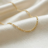 Gold chain necklace on a beige fabric background