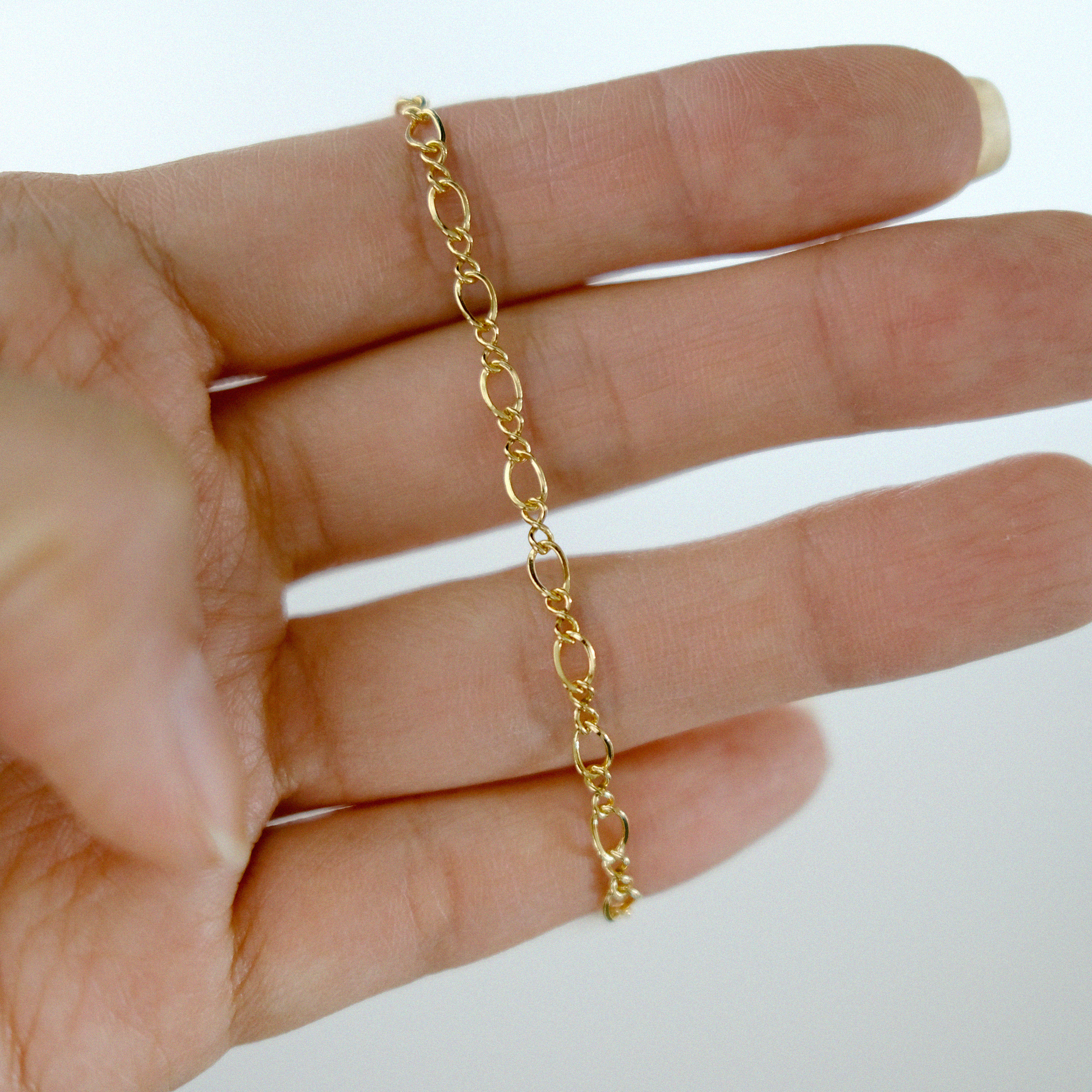 Gold chain on a hand against a white background
