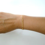 Gold bracelet on a wrist against a white background