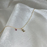 Gold Filled Initial Necklace with birthstone placed on shimmery fabric
