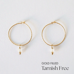 Gold-filled hoop earrings with natural moonstone charms laid flat on a white background